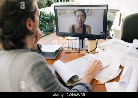 Männlicher Architekt bei Videogesprächen mit weiblicher Kollegin über den Computer im Heimbüro Stockfoto