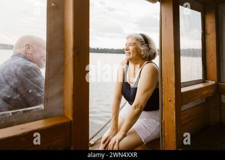 Glückliche Seniorin, die mit Mann auf dem Hausboot sitzt Stockfoto