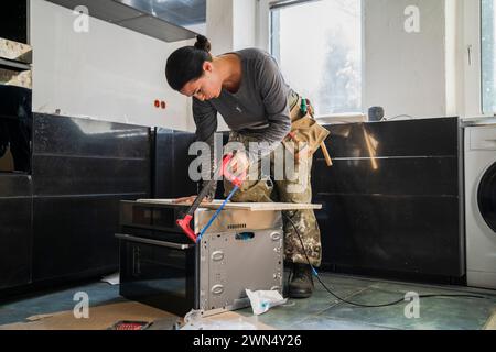 Zimmermann schneidet in der Küche in der Wohnung eine Planke auf der Mikrowelle Stockfoto