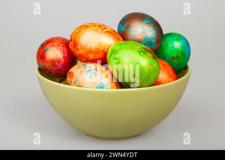 Bunte handbemalte ostereier in einer pastellfarbenen Keramikschale auf grauem Hintergrund Stockfoto