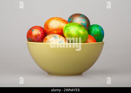 Bunte handbemalte ostereier in einer pastellfarbenen Keramikschale auf grauem Hintergrund Stockfoto