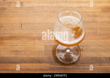 Halbvolles Glas Craft Beer in Tulpenglas auf einem rustikalen Holztisch Stockfoto