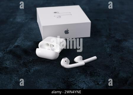 Kabellose Apple Kopfhörer mit einer Verpackung auf dunklem Hintergrund. Stockfoto