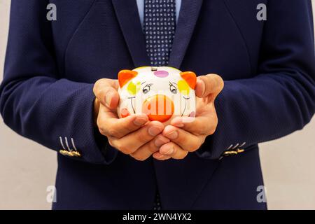 Geschäftsmann, der eine Sparkasse in den Händen hält, Symbol für Ersparnisse und gute Investitionen. Stockfoto