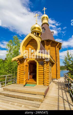 Wunderschöner Blick auf die Holzkirche St. Apostel Andrew, die zuerst am Fluss Vuoksa mit Brücke genannt wurde. Tempel auf einer kleinen Insel in der Nähe des Dorfes Vasilevo Stockfoto