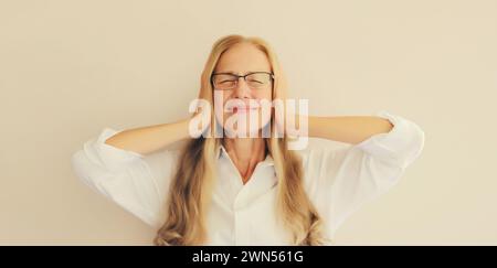 Erschöpfte, müde Angestellte mittleren Alters mit Kopfschmerzen oder Schläfenschmerzen, leidet an Migräne, Verspannungen im Kopf zu Hause Stockfoto