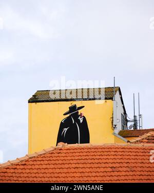 Porto, Portugal - 26. April 2015: Graffiti von Sandemans ikonischer Silhouette des Don mit einem Glas Rotwein über gekachelten Dächern. Stockfoto