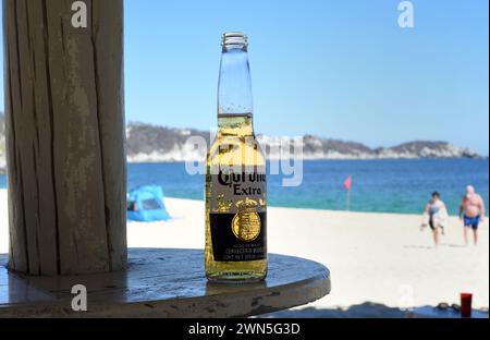 Eine Flasche Corona Extra Bier steht auf einem Tisch am Strand in Huatulco, Oaxaca, Mexiko. Im Ausland leben Stockfoto