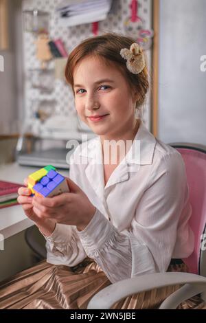 Jekaterinburg, Russland, 14. Februar 2024: Süßes Mädchen zu Hause löst einen rubik-Würfel. Es wurde 1974 vom ungarischen Architekten Erno Rubik erfunden. Stockfoto