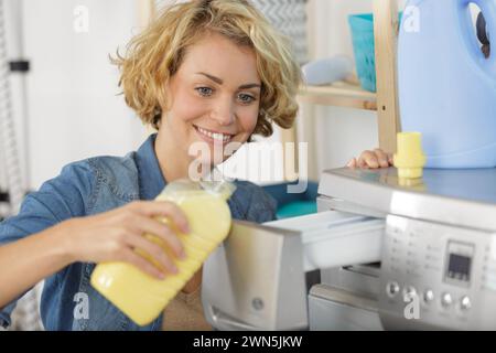 Frau, die einen Weichspüler in der Waschmaschine hinzufügt Stockfoto