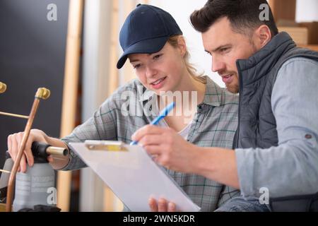 Ingenieure lesen die Zwischenablage, während sie im Temperaturkontrollraum arbeiten Stockfoto