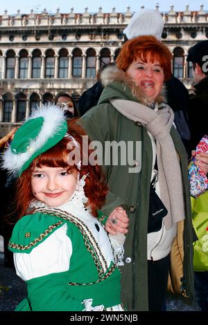 Wunderschönes stolzes und glückliches kleines Mädchen beim Karneval in Venedig mit ihrer Großmutter in St. Marks Platz Stockfoto