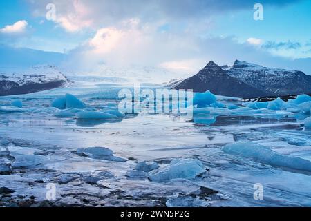 Gletschersee mit Eisbergen und gefrorenem Wasser mit Bergen im Hintergrund Stockfoto