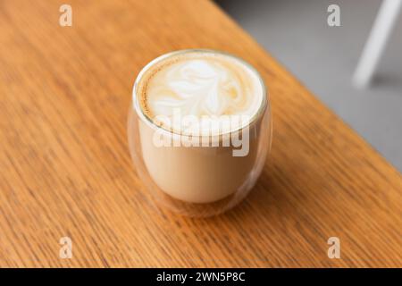Ein Glas Cappuccino-Kaffee steht auf Holztisch, Nahaufnahme mit selektivem Fokus Stockfoto