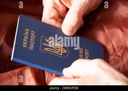 Hände einer alten Frau halten einen ukrainischen Ausländerpass in Nahaufnahme, ukrainischer Pass Stockfoto