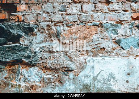 Rote Ziegelwand in den Rissen. Zerbrochene Ziegelmauer aus der Nähe. Alte Mauerruine. Baufällige Ziegelmauer. Urbane Textur. Ziegelwand mit Schleifstruktur b Stockfoto