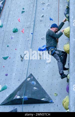 Ältere Kletterer arbeiten sich an einer Kletterwand hinauf Stockfoto