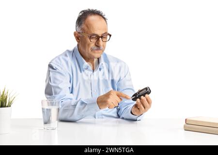 Reifer Mann mit einem Glukosemonitor isoliert auf weißem Hintergrund, Diabetes und Gesundheitskonzept Stockfoto