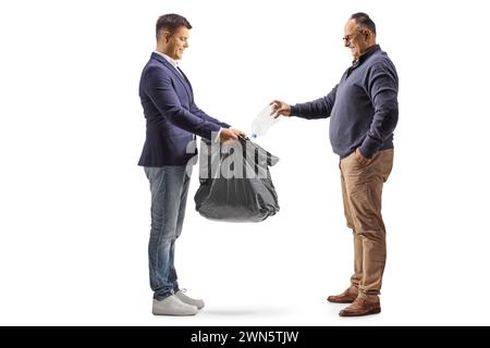 Profilaufnahme eines Reifen Mannes, der eine Plastikflasche in einen schwarzen Abfallbeutel wirft, isoliert auf weißem Hintergrund Stockfoto