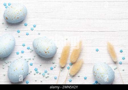 Blaue Ostereier, Spikelets und Konfetti auf weißem Holzhintergrund, Blick von oben mit Kopierraum. Stockfoto