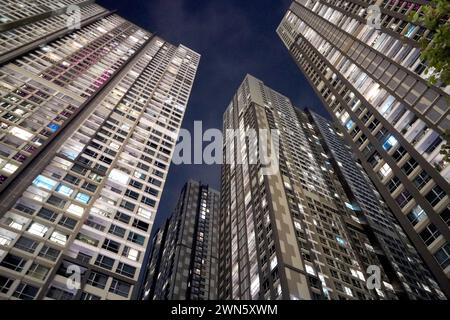 Niedriger Blick auf moderne Wolkenkratzer bei Nacht, die sich über ihnen erheben Stockfoto
