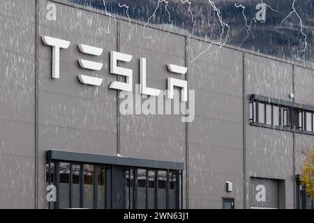 Deutschland - 29. Februar 2024: Das Logo des E-Car-Herstellers Tesla, auf einer Hauswand, mit Gewitter und Regenwolken. Symbolisches Bild für den Skandal bei Tesla. FOTOMONTAGE *** das Logo des E-Auto-Herstellers Tesla, an einer Hauswand, mit Gewitter- und Regenwolken. Symbolbild für Skandal bei Tesla. FOTOMONTAGE Stockfoto