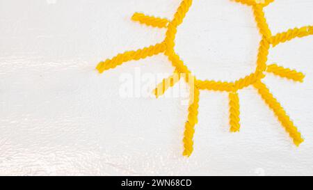 Sonne aus Fusilli Pasta, grünes Feld aus grüner Spirale Pasta auf weißem Hintergrund Stockfoto