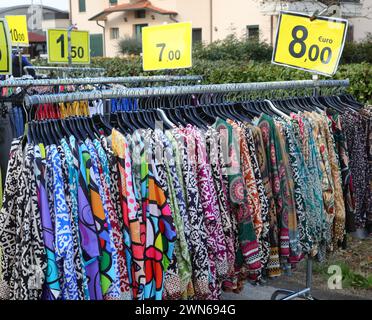 Kleider für Damen und farbenfrohe Blusen aus Baumwolle oder Polyester hängen an Kleiderbügeln, die im Winter auf dem Freiluftmarkt verkauft werden Stockfoto