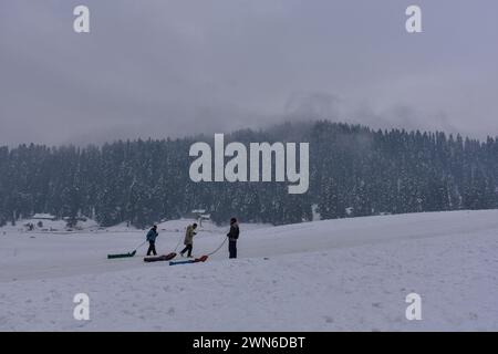 Gulmarg, Kaschmir, Indien. Februar 2024. Kaschmiri-Männer mit Schlitten laufen auf dem schneebedeckten Feld im Skigebiet Gulmarg, etwa 55 km von Srinagar, der Sommerhauptstadt von Jammu und Kaschmir, entfernt. (Credit Image: © Saqib Majeed/SOPA Images via ZUMA Press Wire) NUR REDAKTIONELLE VERWENDUNG! Nicht für kommerzielle ZWECKE! Stockfoto