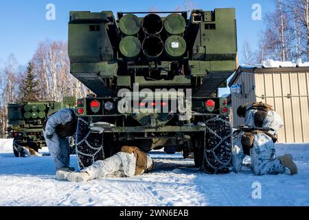 U.S. Marines mit Fox Battery, 2. Bataillon, 14. Marine Regiment, 4. Marine Division, Marine Forces Reserve befestigen Schneeketten an den Reifen eines High Mobility Artillery Rocket System (HIMARS) Fahrzeugs, bevor sie mit einer HIMARS Rapid Infiltration beginnen, auch bekannt als HIRAIN, während der Übung Arctic Edge 2024 auf der Eielson Air Force Base, Alaska, 24. Februar 2024. Das HIMARS-Waffensystem ist ein wichtiger Bestandteil des Ground Combat Elements in der Marine Air-Ground Task Force (MAGTF). HIMARS spielen eine zentrale Rolle bei der Bereitstellung von Präzisionsbränden mit weiträumiger Reichweite, um die Ziele der MAGTF zu unterstützen, von Expeditionsprojekten aus Stockfoto