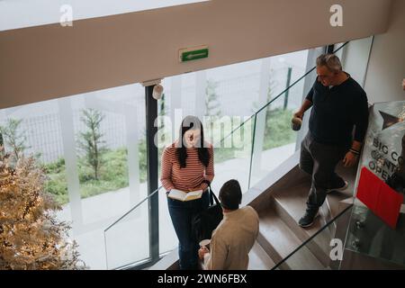 Hochwinkelaufnahme einer modernen Bürolobby, in der Einzelpersonen lesen, laufen und sich unterhalten können, in einer geschäftlichen und ungezwungenen Atmosphäre. Stockfoto