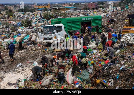 Nairobi, KENIA. Februar 2024. Abfallsammler, die Abfallprodukte aus einem Müllwagen entladen, um sie auf der Dandora-Deponie in Nairobi, Kenia, zu sammeln. Dandora ist ein Slum in Nairobi Kenia, das 1977 gegründet wurde. Im Inneren des Dandora-Slums befindet sich eine der größten und bekanntesten Deponien von Dandora. Die 30 Hektar große Anlage mit an.estimated 850 festen Abfällen aus ganz Nairobi wurde 1975 gegründet. Jede Minute laden die Müllsammler am.Standort Abfälle von den verschiedenen Lkws ab, die am.Standort ankommen. Die Müllsammler, die auch aus verschiedenen Teilen der Dandora-Slums leben Stockfoto