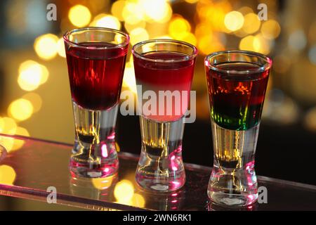 Verschiedene Schützen in Schussgläsern auf der Oberfläche vor verschwommenem Hintergrund, Nahaufnahme Alkohol trinken Stockfoto