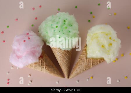 Süße Baumwollbonbons in Waffelkegeln auf beigefarbenem Hintergrund, flacher Lay Stockfoto
