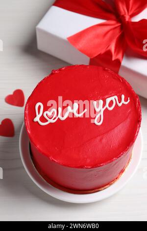 Bento Kuchen mit Text Love You, Geschenkbox und Papierherzen auf weißem Holztisch. St. Valentinstag-Überraschung Stockfoto