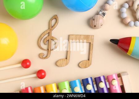 Baby-Lied-Konzept. Hölzerne Notizen, Kinder Xylophon und Spielzeug auf beigefarbenem Hintergrund, flache Lagen Stockfoto