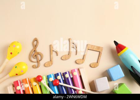 Baby-Lied-Konzept. Hölzerne Notizen, Kinder Xylophon und Spielzeug auf beigefarbenem Hintergrund, flache Lagen. Leerzeichen für Text Stockfoto