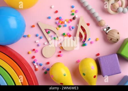 Baby-Lied-Konzept. Hölzerne Notizen, Maracas für Kinder und Spielzeug auf rosafarbenem Hintergrund, flache Lagen Stockfoto