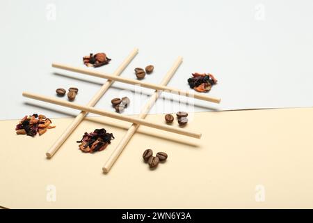 TIC Tac Toe Spiel mit Kaffeebohnen und trockenen Teeblättern auf farbigem Hintergrund Stockfoto