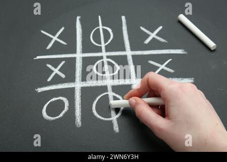 Frau spielt Tic Tac Toe auf Tafel, Nahaufnahme Stockfoto