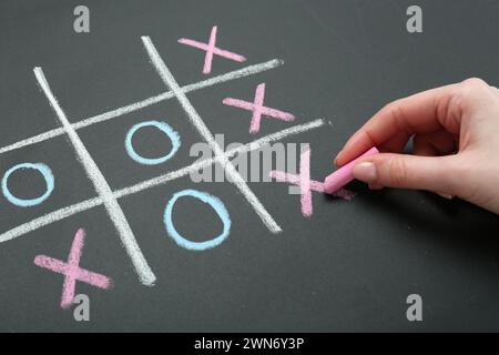 Frau spielt Tic Tac Toe auf Tafel, Nahaufnahme Stockfoto