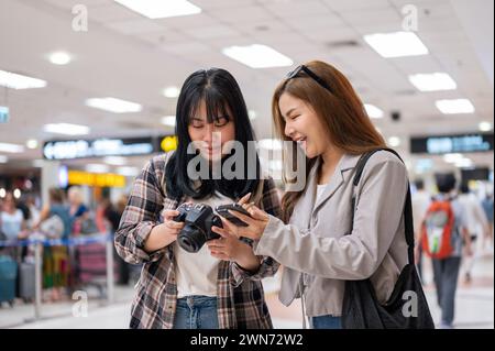 Zwei fröhliche asiatische Freundinnen Reisende Fluggäste sprechen während sie am Flughafen laufen und zusammen reisen. Menschen- und Transportkonzepte Stockfoto