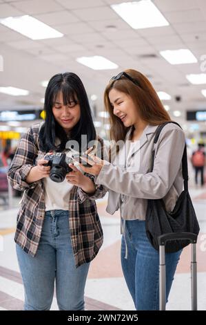 Zwei fröhliche asiatische Freundinnen Reisende Fluggäste sprechen während sie am Flughafen laufen und zusammen reisen. Menschen- und Transportkonzepte Stockfoto