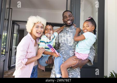 Afroamerikanischer Soldat in Militäruniform mit seiner Familie vor ihrem Haus Stockfoto