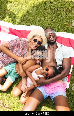 Die afroamerikanische Familie genießt einen sonnigen Tag im Freien und liegt auf einer bunten Decke Stockfoto