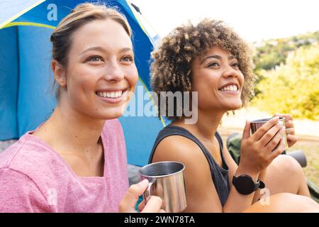 Die junge weiße Frau und die junge birassische Frau genießen einen Campingmorgen Stockfoto