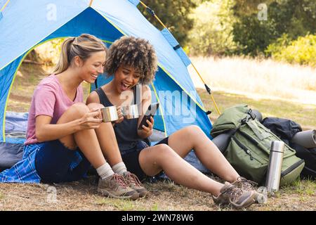 Junge kaukasische Frau und birassische Frau lachen vor einem Zelt Stockfoto