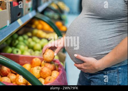 Schwangere Frau wählt Äpfel im Laden. Stockfoto