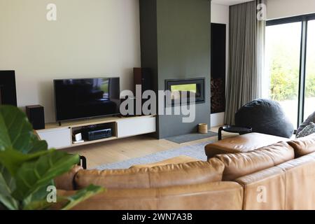 Das moderne Wohnzimmer verfügt über einen großen Fernseher, einen Kamin und bequeme Sitzmöbel mit Kopierbereich Stockfoto