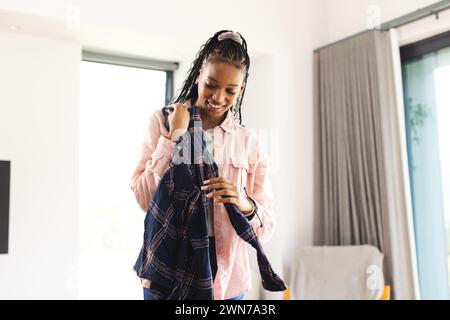 Eine junge Afroamerikanerin lächelt, während sie ein Hemd anprobiert Stockfoto